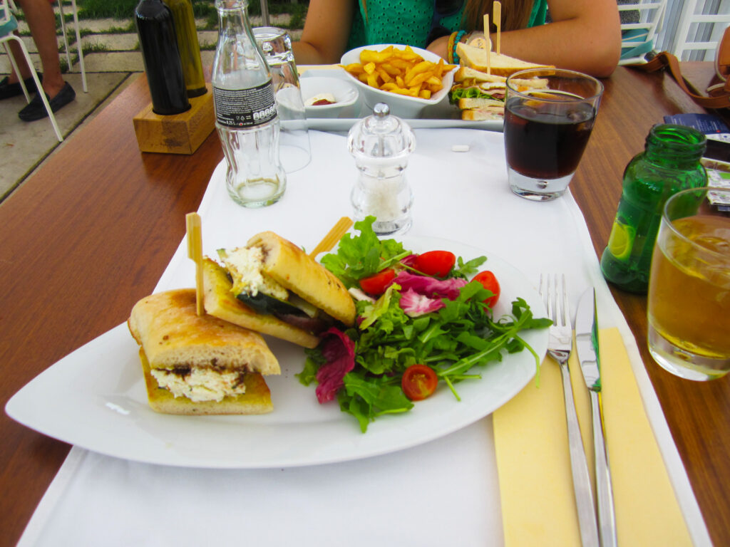 Täytettyjä leipiä ja salaattia lautasella. Toisella lautasella näkyy ranskalaisia. Lounas Kroatiassa.